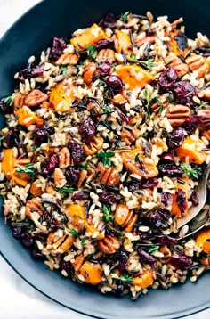 a bowl filled with rice, nuts and dried cranberries on top of a table