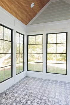 an empty room with large windows and tiled floor