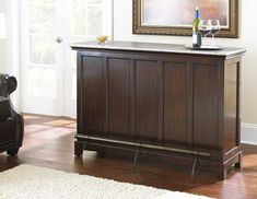 a living room with a chair, table and wine bottle on top of the cabinet