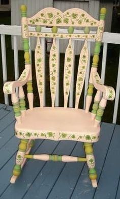 a wooden rocking chair sitting on top of a blue deck next to a white fence