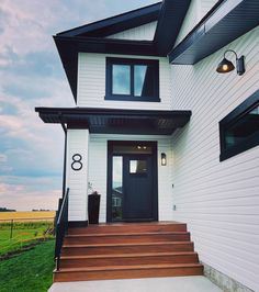 a white house with black trim and wood steps