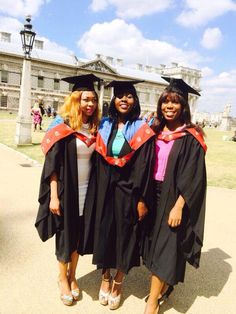 three women in graduation gowns and caps posing for a photo together at the university