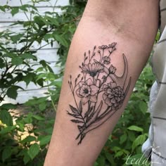 a black and white flower tattoo on the left arm, with flowers in it's center