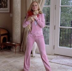 a woman in pink is holding a stuffed animal and posing for the camera with her hands behind her back