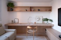 a living room with a couch, desk and shelves on the wall next to it