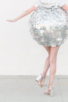 a woman in a silver sequin skirt with her arms spread out to the side