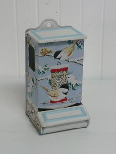 a bird feeder with two birds on it's sides and a pine tree in the background