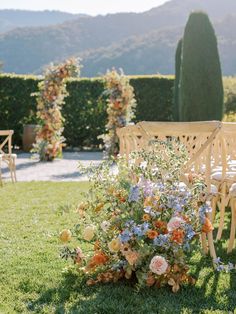 a wooden bench sitting in the middle of a lush green field next to a flower filled planter