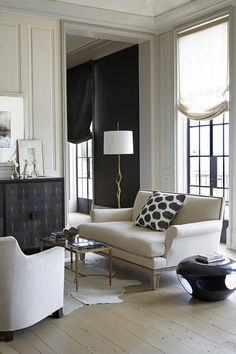 a living room filled with white furniture and black curtains on the windows sills