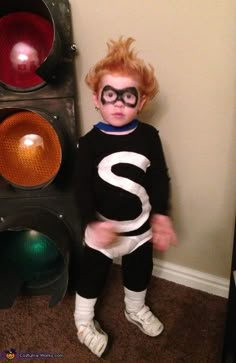 a young child dressed as a nerd standing in front of a traffic light with the letter s on it