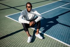 a man sitting on top of a tennis court holding a racquet