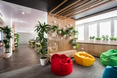 colorful bean bag chairs in an office lobby with plants on the wall and wooden slats behind them