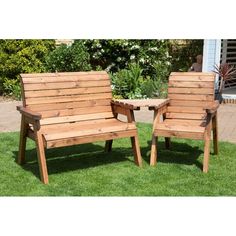 two wooden chairs sitting on top of grass next to each other in front of a house