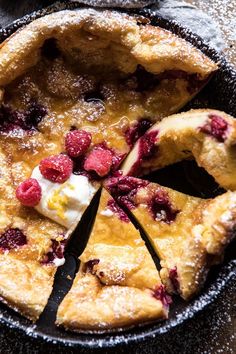 a pie with raspberries and cream on top in a skillet, ready to be eaten