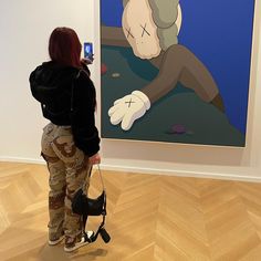 a woman taking a photo of a painting in an art gallery with her cell phone