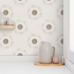 a white vase sitting on top of a counter next to a wallpapered wall