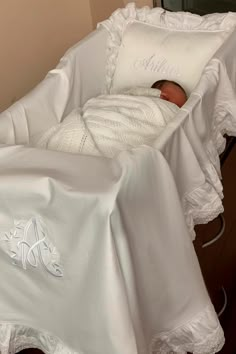 a baby is laying in a crib with white sheets on it's sides