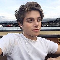 a young man with ear buds on his ears looking at the camera while wearing headphones