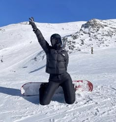 a snowboarder sitting on the ground with his arms in the air