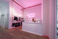 there is a woman sitting at the counter in front of some shirts and shorts on display