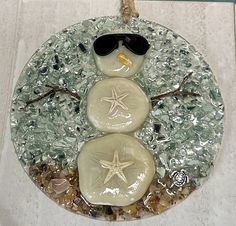 a snowman made out of sea glass with sunglasses on it's head and starfish in the middle