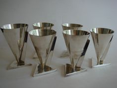 five silver cups are lined up on metal stands