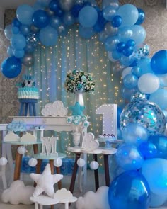 blue and white balloons are hanging from the ceiling in front of a table with cake