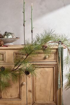 pine cones and candles are on top of a dresser