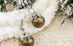 two gold christmas balls hanging from the side of a white furnishing with snow flakes in the background