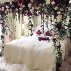 a bed covered in lots of flowers and greenery