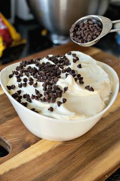 a bowl filled with ice cream and chocolate chips on top of a wooden cutting board