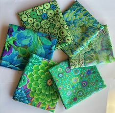 four square pieces of green and blue fabric with flowers on them, all folded together