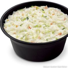 a black bowl filled with coleslaw on top of a white table next to a knife