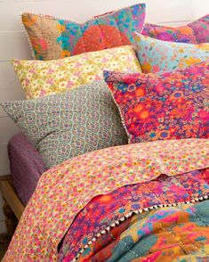 a bed covered in lots of colorful pillows