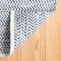 a blue and white area rug on top of a wooden floor next to a wood floor