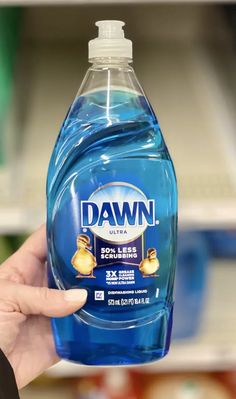 a hand holding a bottle of dawn dishwasher detergent in front of a store shelf