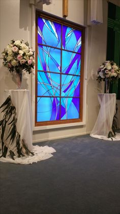 two vases filled with flowers sit in front of a stained glass window on the floor