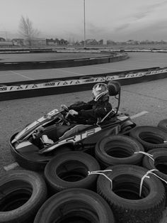 a black and white photo of a person in a race car with lots of tires