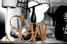 the word sew spelled out in front of a lamp and other items on a table