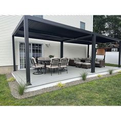 a patio covered in black and white furniture next to a house with a table and chairs on it