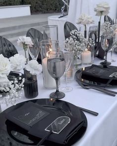 the table is set with black and white plates, silverware, candles and flowers