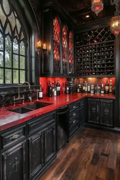 a kitchen with black cabinets and red counter tops is pictured in this image, there are many wine bottles on the shelves