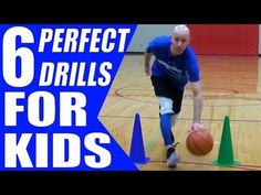 a young man dribbling a basketball on an indoor court with cones around him