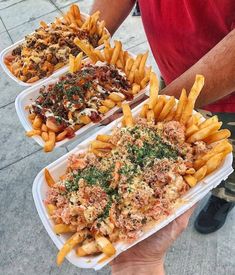 three trays filled with different types of food on top of each other in front of a man's hand