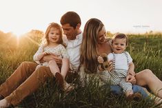 a man, woman and child are sitting in the grass