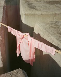 a pink shirt is hanging on a clothesline near some concrete blocks and cement steps