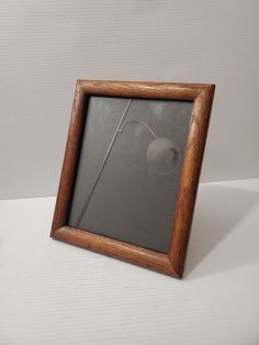 a wooden frame with a flower in it on a white tableclothed surface next to a wall