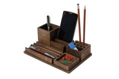 a wooden desk organizer with pens, pencils and an electronic device in the holder