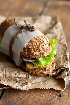 a sandwich wrapped in paper on top of a wooden table