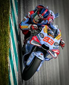 a man riding on the back of a motorcycle down a race track with grass behind him